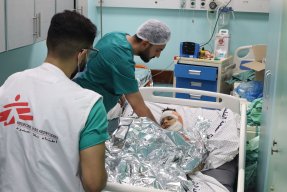 Medicinsk personal vid en sjukhussäng med en pojke med bandage runt huvudet
