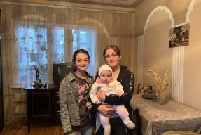 Porträttbild på en mamma med sitt tonårsbarn och sin bebis. 