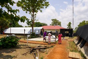 En kvinna på bår rullas in i ett tältsjukhus.