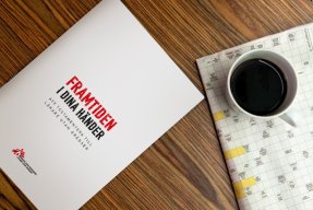 Läkare Utan Gränsers testamentesbroschyr bredvid en kopp kaffe och ett korsord.