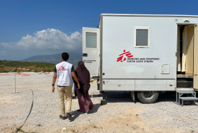En anställd på Läkare Utan Gränser och en patient går mot mobil klinik