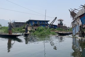 Två män i varsin båt tar sig mellan raserade hus
