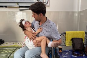 Man med sitt skadade barn i famnen på ett sjukhus i Gaza