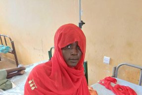 Kvinna sittandes på sjukhussäng