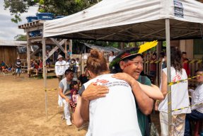 En person i Läkare Utan Gränser-väst kramar om en person med fjäderhuvudbonad och ansiktsmålning.