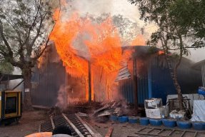 En brinnande byggnad med två människor i förgrunden.