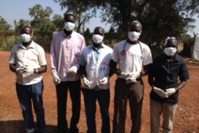 Fem MSF-anställda på rad med munskydd och skyddshandskar.