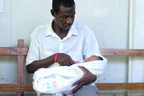 Stolt far med sitt nyfödda barn på förlossningskliniken i Haiti.