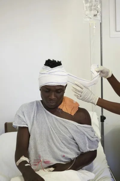 En man med bandage på huvudet tas hand om av medicinsk personal