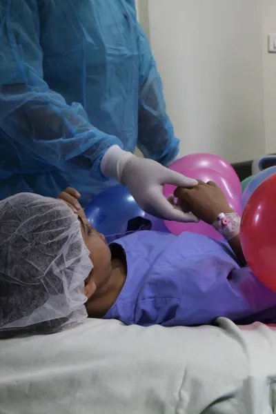 Salwa ligger på en bår med ballonger på sig