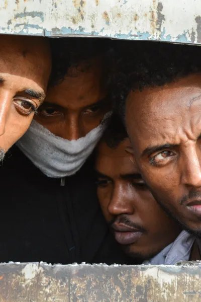 Fyra män tittar ut från ett förvar i Libyen.