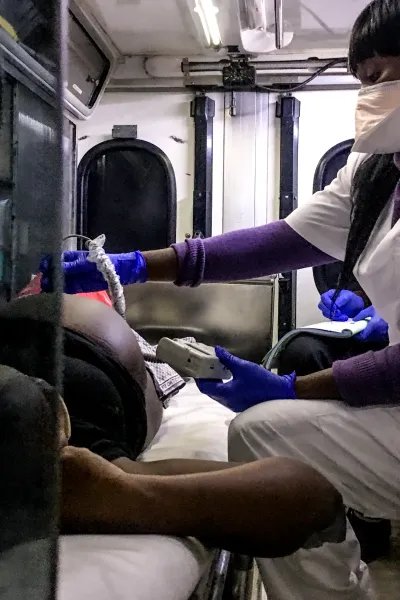 En kvinna gör ett ultraljud på en gravid kvinna som ligger på en bår i en ambulans.