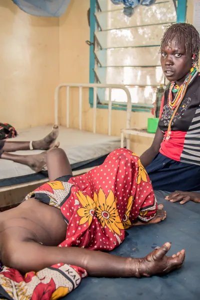 En flicka som blivit ormbiten ligger på en brits på ett sjukhus i Kenya, hennes mamma sitter bredvid och tittar in i kameran. 