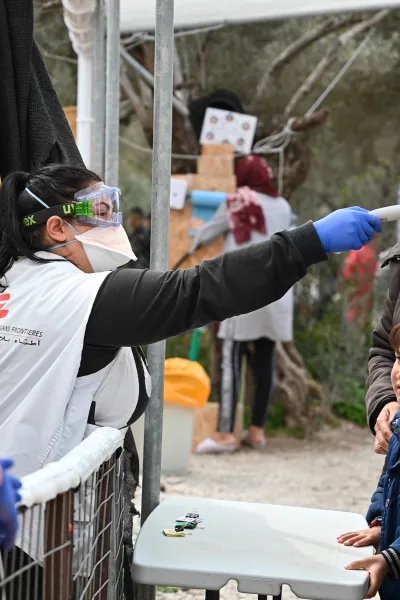 Medicinsk personal tar temperaturen på ett barn i flyktinglägret Moria, på den grekiska ön Lesbos.