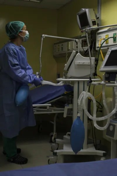 En medicinsk personal står iklädd skyddsutrustning och tittar på en monitor.
