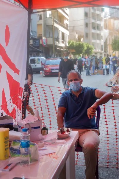 En man sitter på en stol och får vård vid en mobil klinik efter explosionen i Beirut, Libanon.