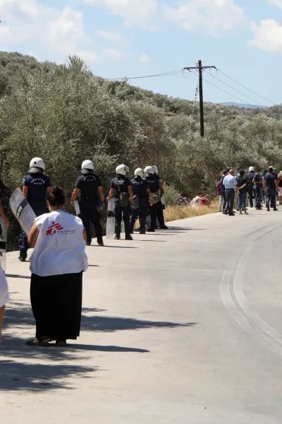 Personal från Läkare Utan Gränser tittar på när polisen för bort demonstranter utanför Moria, på den grekiska ön Lesbos.