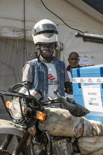 En man står vid en motorcykel vid en vaccinationskampanj mot mässling i Kongo-Kinshasa.
