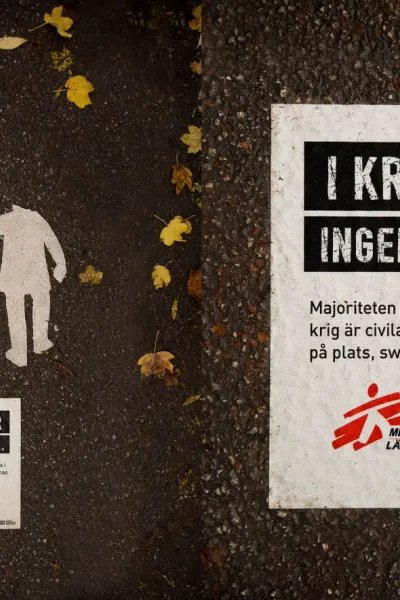 En bild på ett trasigt övergångställe med en skylt av Läkare Utan Gränser bredvid där det står "I krig går ingen säker"