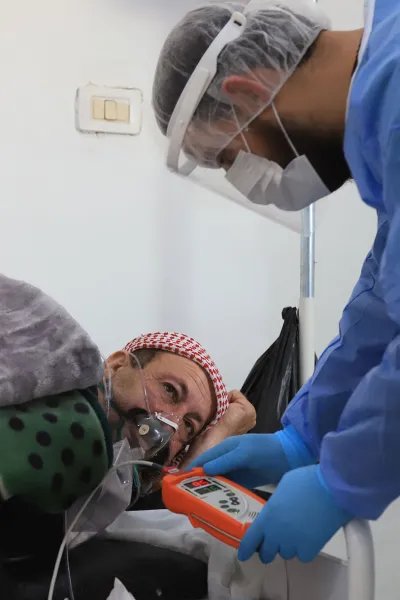 En sjuksköterska tittar till en patient med misstänkt covid-19 på sjukhuset i Idlib, Syrien.