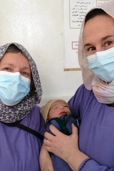 Barnmorskorna Astrid och Lena håller i en nyfödd bebis, på Khost kvinnorsjukhus i Afganistan.