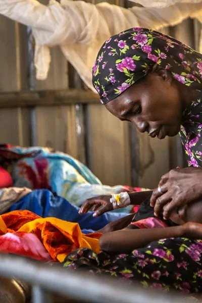Rauda Adam Isa klappar sin dotter på pannan i en sjukhussäng på sjukhuset El Fasher, norra Darfur, Sudan.