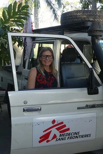 Sjuksköterskan Ulli Hedberg, som är i Haiti, står bakom en bildörr och tittar in i kameran.