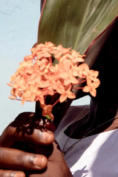 En kvinna i Centralafrikanska republiken håller en blomma framför sitt ansikte.