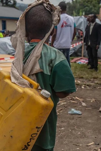 Ett barn i Sake bär på en vattendunk, efter vulkanen Nyiragongos utbrott i Kongo-Kinshasa