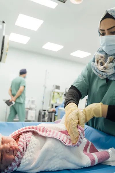 En nyfödd bebis på Nablus sjukhus i västa Mosul, Irak, sveps in i en filt av en sjukvårdspersonal.