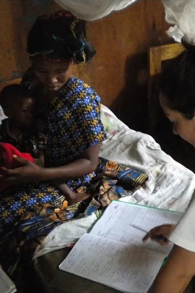 Läkaren Jennifer Turnbull sitter på en säng på Mweso sjukhus i Kongo-Kinshasa. På andra sidan sängen sitter en mamma med sitt lilla barn.