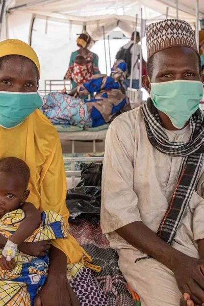 Ali, som vårdas på sjukhuset  i Magaria i Niger för malaria och uttorkning, sitter i sin mammas knä på en säng.