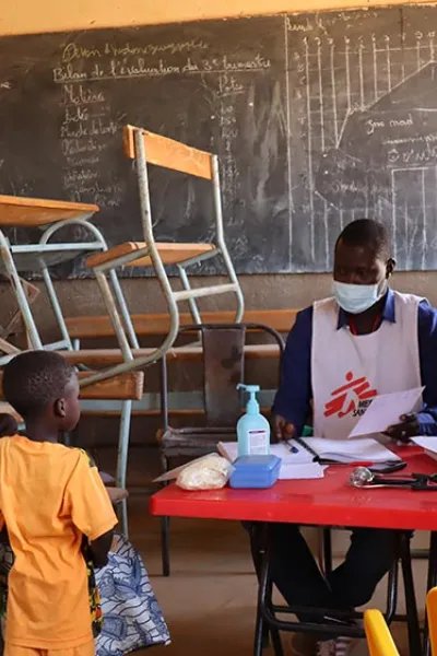 En pojke, som står bredvid sin mamma, träffar personal från Läkare Utan Gränser på en mobil klinik i Titao, Burkina Faso. 