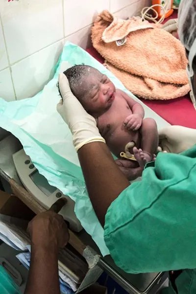 En nyfödd bebis ligger i händerna på sjukvårdspersonal på Läkare Utan Gränsers mödravårds- och förlossningsklinik  i Jahun, norra Nigeria.