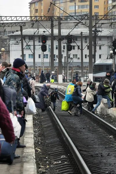 Människor med bagage korsar tågspåren i den ukrainska staden Lviv.