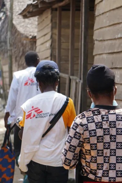 Tre medarbetare går längs en sandig väg mot byn Enyenge i Kamerun.
