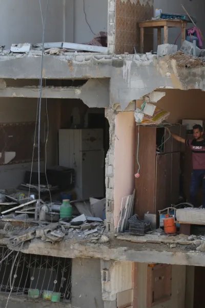 Ett flervåningshus i Gaza, Palestina, som bombats. På en av våningsplanen står en man och tittar ut.