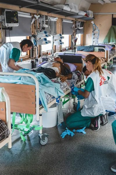 Personal på intensivvårdsavdelningen på Läkare Utan Gränsers tåg övervakar och stabiliserar en svårt krigsskadad patient under en resa från Pokvrosk i östra Ukraina till Lviv i västra Ukraina.