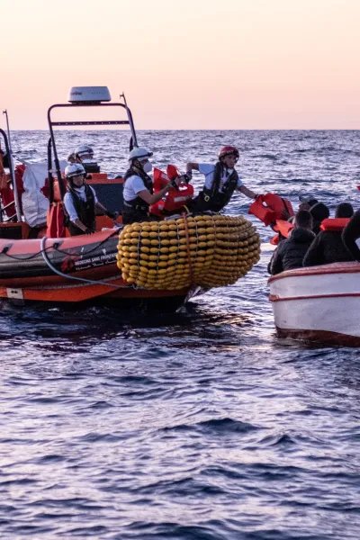 En gummibåt från Läkare Utan Gränsers sök- och räddningsfartyg Geo Barents undsätter en grupp människor från en träbåt på centrala Medelhavet.