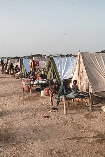 Människor sitter i tillfälliga skydd byggda på en väg i översvämningsdrabbade Pakistan.