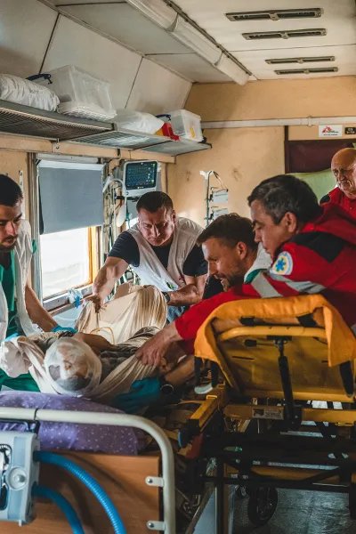 I en tågvagn flyttar Läkare Utan Gränsers personal en patient från en bår till en säng.