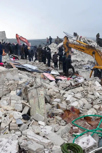 En grävskopa gräver i rasmossorna efter en stora jordbävning som drabbade Turkiet och Syrien.