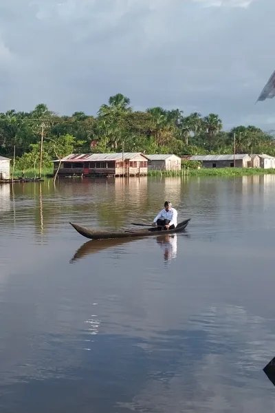 En flod med några enkla träbyggnader i bakgrunden.