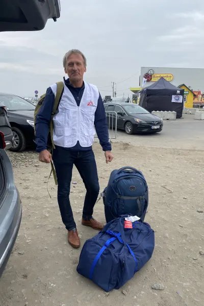 En man med Läakre Utan Gränser väst står bredvid två fullpackade väskor.