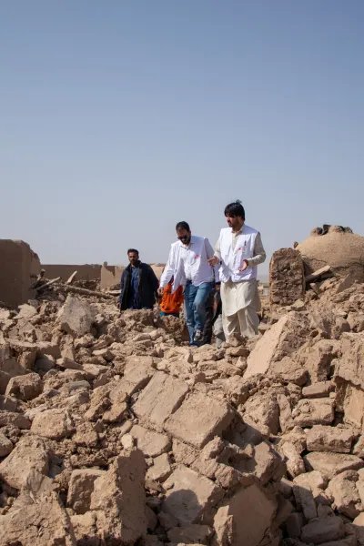 Tre medarbetare från Läkare Utan Gränser går över stora rasmassor efter jordbävningen i Afghanistan
