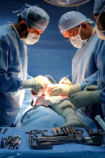 Tre kirurger utför en operation på en patients ben.