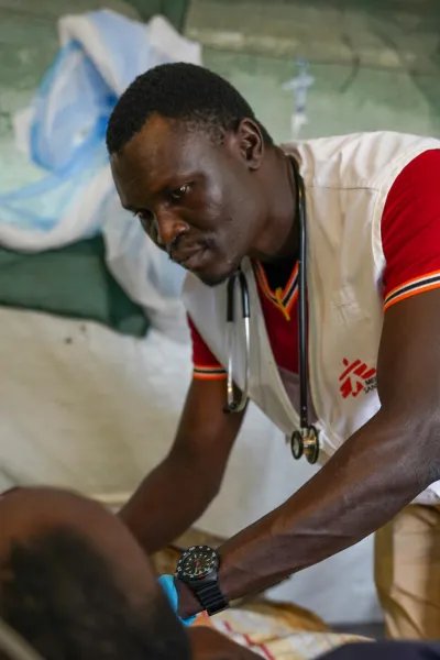 Läkare i Läkare utan gränser väst står böjd över en patient