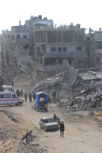 gatuvy i Rafah med sönderbombade byggnader och en ambulans
