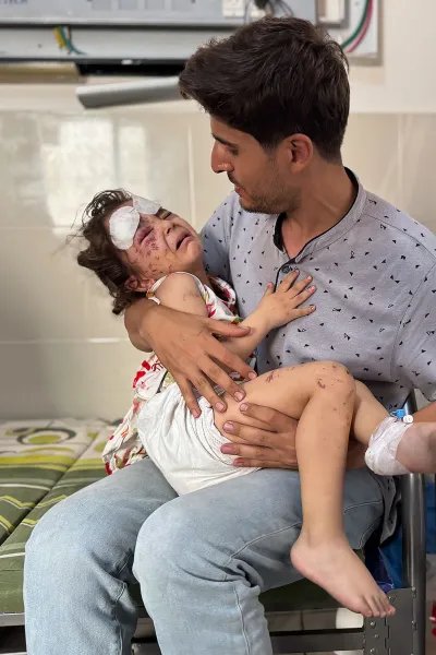 Man med sitt skadade barn i famnen på ett sjukhus i Gaza