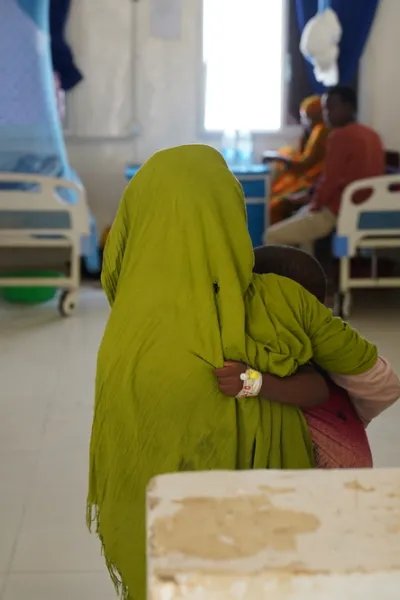 En liten pojke håller i sin syster inne på barnavårdsavdelningen i Somalia.